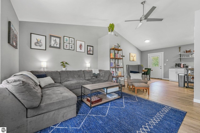 living room with wood finished floors, lofted ceiling, a ceiling fan, and baseboards