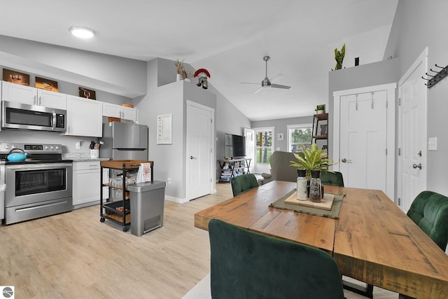 dining space with ceiling fan, light wood-type flooring, baseboards, and high vaulted ceiling