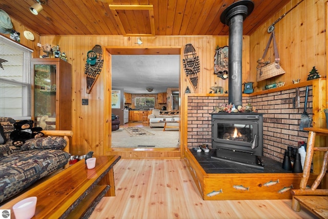 6202 Fletcher Rd, Fife Lake, MI 49633 - living room with a wood stove, wood walls, hardwood / wood-style floors, and wood ceiling