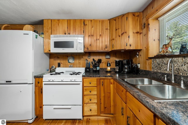 6202 Fletcher Rd, Fife Lake, MI 49633 - kitchen featuring white appliances, a sink, brown cabinets, light wood-style floors, and dark countertops