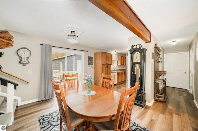 4480 Mockingbird Cir, Farwell, MI 48622 - dining space with light wood-style flooring, beam ceiling, baseboards, a chandelier, and stairs