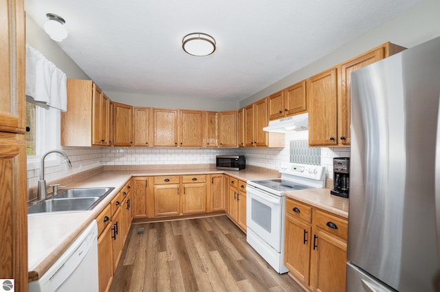 4480 Mockingbird Cir, Farwell, MI 48622 - kitchen featuring stainless steel appliances, a sink, under cabinet range hood, wood finished floors, and light countertops