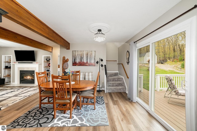 4480 Mockingbird Cir, Farwell, MI 48622 - dining space with light wood-style flooring, a fireplace with flush hearth, beamed ceiling, stairs, and a chandelier