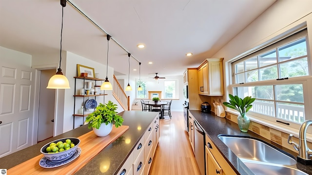 kitchen featuring a sink, dishwasher, a ceiling fan, pendant lighting, and light wood-style floors