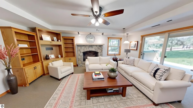 living area featuring a ceiling fan, a fireplace, and light colored carpet