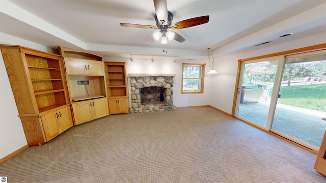 unfurnished living room featuring a stone fireplace, ceiling fan, baseboards, and light carpet