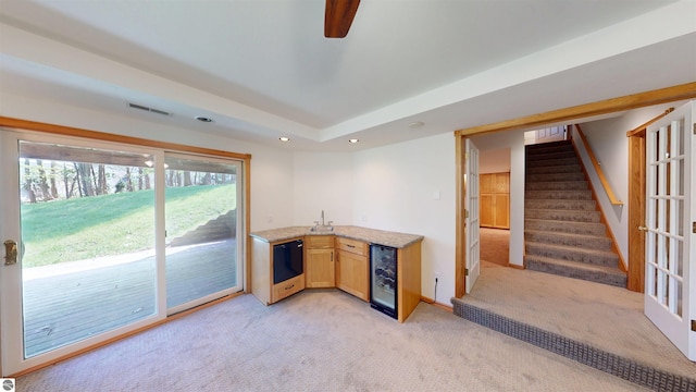 kitchen with wine cooler, light carpet, a sink, recessed lighting, and light stone counters
