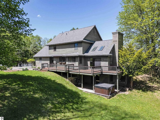 rear view of property with a hot tub, a deck, a chimney, a yard, and a shingled roof