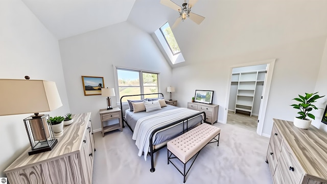 bedroom featuring high vaulted ceiling, a skylight, baseboards, a walk in closet, and light colored carpet
