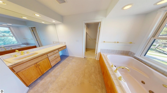 bathroom with vanity, healthy amount of natural light, recessed lighting, and a jetted tub