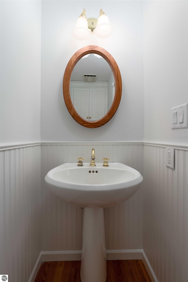 bathroom featuring wood finished floors, wainscoting, and baseboards