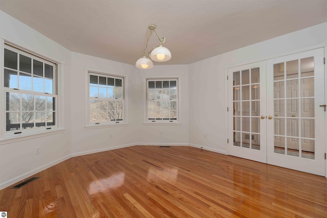 empty room featuring light wood-style floors, baseboards, and french doors