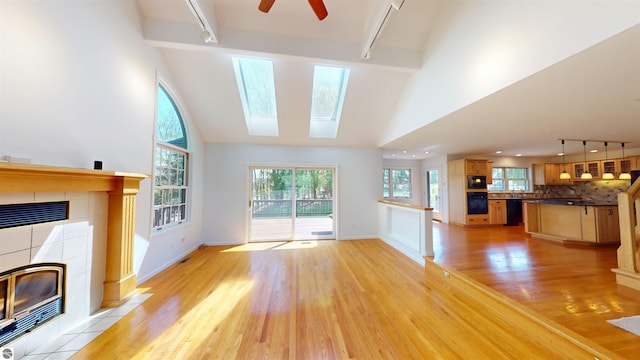 unfurnished living room featuring rail lighting, a fireplace, light wood-style floors, healthy amount of natural light, and beamed ceiling