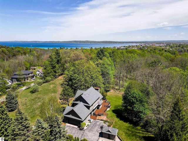 view from above of property with a nearby body of water and a heavily wooded area