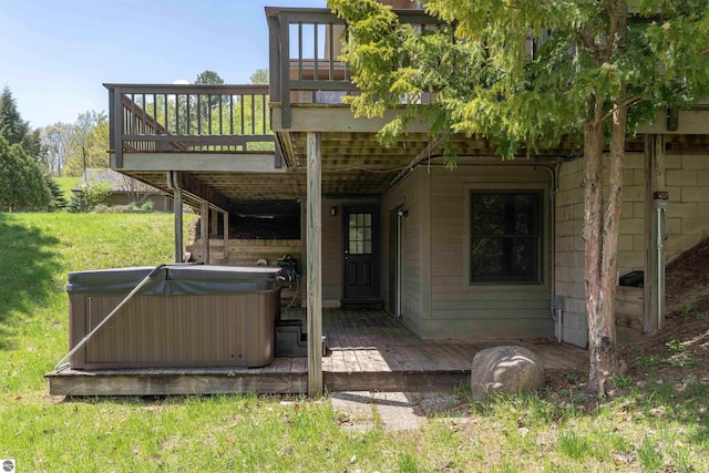 back of property featuring a hot tub, a deck, and a yard