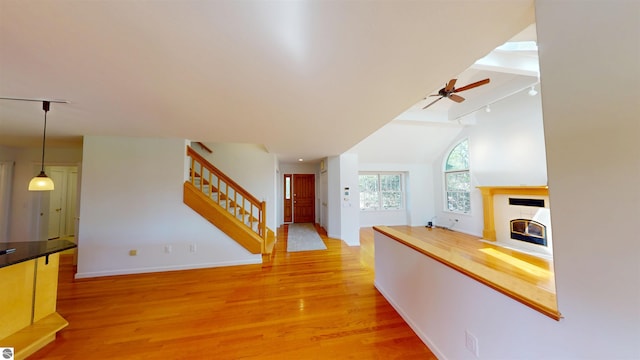 hallway with stairs, light wood-style flooring, baseboards, and vaulted ceiling