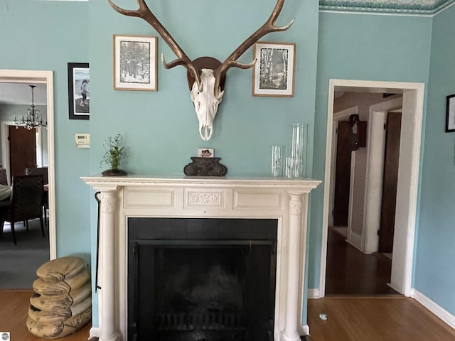 630 N State St, Alma, MI 48801 - detailed view of wood finished floors, a chandelier, a fireplace, and baseboards