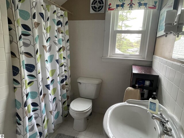 630 N State St, Alma, MI 48801 - bathroom featuring tile walls, a sink, tile patterned floors, toilet, and a wainscoted wall