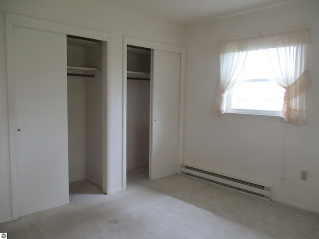8481 N Luce Rd, Alma, MI 48801 - unfurnished bedroom featuring a baseboard heating unit, light colored carpet, and multiple closets