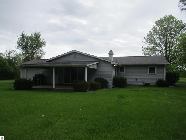 8481 N Luce Rd, Alma, MI 48801 - rear view of property featuring a lawn, a chimney, and a patio area