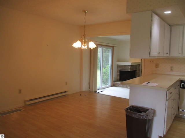 8481 N Luce Rd, Alma, MI 48801 - kitchen featuring a baseboard radiator, light wood-type flooring, white cabinets, a brick fireplace, and light countertops