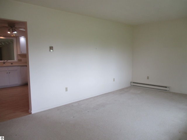 8481 N Luce Rd, Alma, MI 48801 - spare room featuring a baseboard radiator, light colored carpet, ceiling fan, and a sink