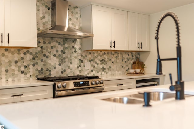 968 Barlow St, Traverse City, MI 49686 - kitchen with wall chimney exhaust hood, stainless steel gas stove, decorative backsplash, light countertops, and white cabinetry
