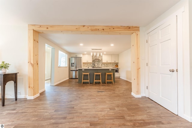 968 Barlow St, Traverse City, MI 49686 - kitchen featuring stainless steel fridge, white cabinetry, a kitchen breakfast bar, tasteful backsplash, and recessed lighting