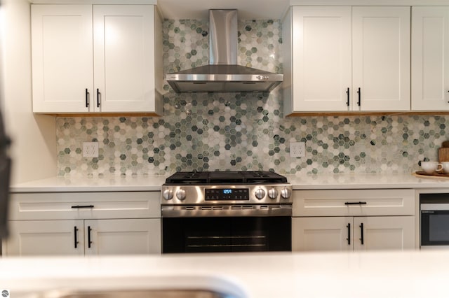 968 Barlow St, Traverse City, MI 49686 - kitchen featuring gas range, wall chimney exhaust hood, light countertops, white cabinetry, and decorative backsplash