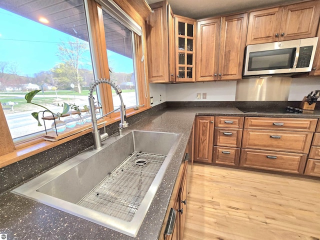 205 S Elm St, Suttons Bay, MI 49682 - kitchen featuring stainless steel microwave, a sink, black electric stovetop, brown cabinets, and dark countertops