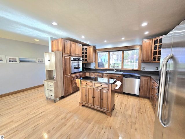 205 S Elm St, Suttons Bay, MI 49682 - kitchen with appliances with stainless steel finishes, a sink, dark countertops, light wood-type flooring, and a kitchen island