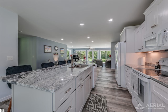 1703 Rau Rd, West Branch, MI 48661 - kitchen with white appliances, a sink, open floor plan, a kitchen breakfast bar, and white cabinetry