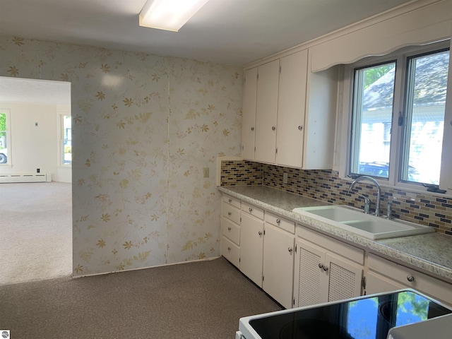 kitchen featuring a sink, carpet, stove, a baseboard heating unit, and tasteful backsplash