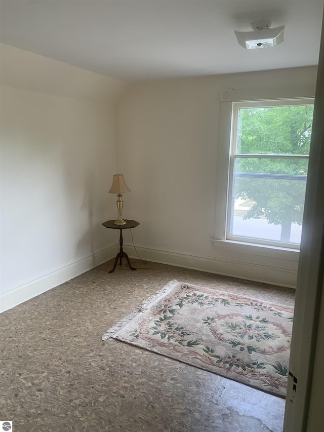 empty room with vaulted ceiling and baseboards