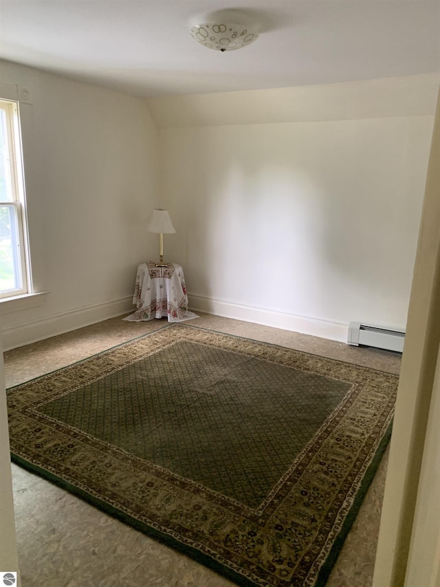 empty room with baseboard heating, baseboards, and vaulted ceiling