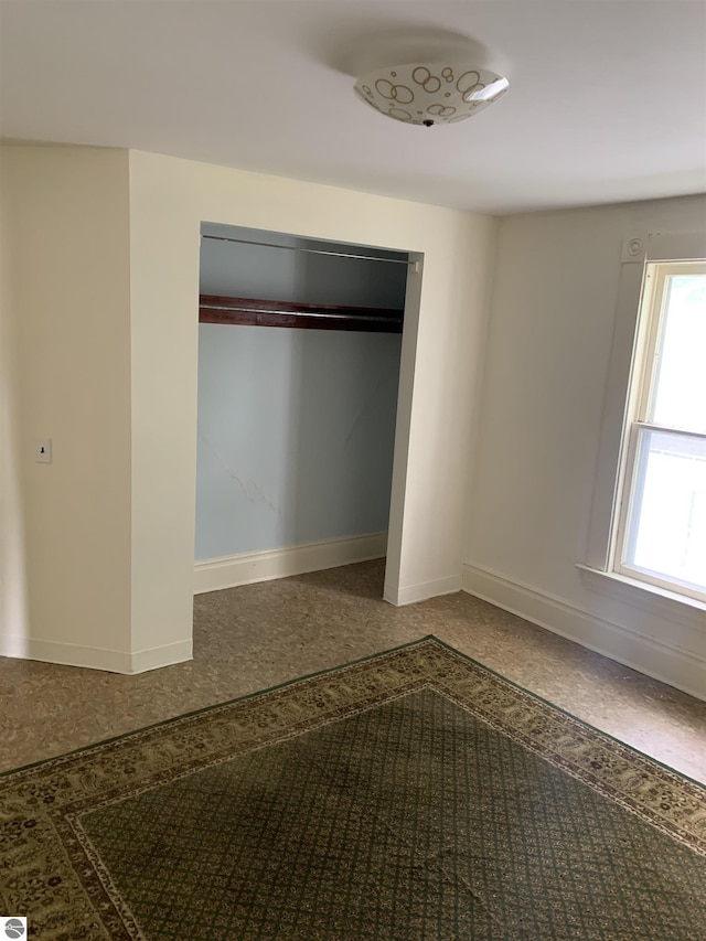 unfurnished bedroom with baseboards and speckle patterned floor
