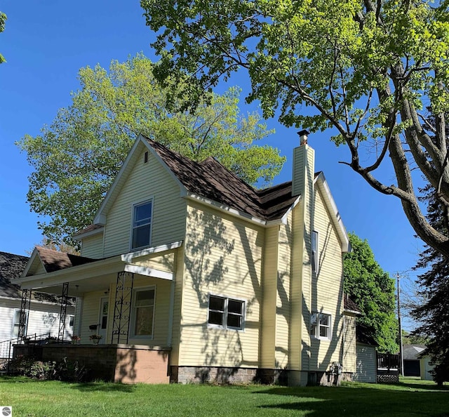 view of home's exterior with a chimney, a lawn, and a porch