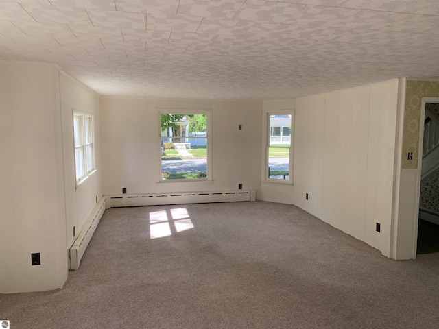 carpeted empty room featuring baseboard heating