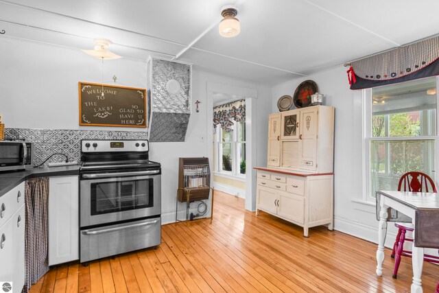 302 N Rose St, Northport, MI 49670 - kitchen featuring stainless steel appliances, light wood-style floors, white cabinetry, dark countertops, and baseboards