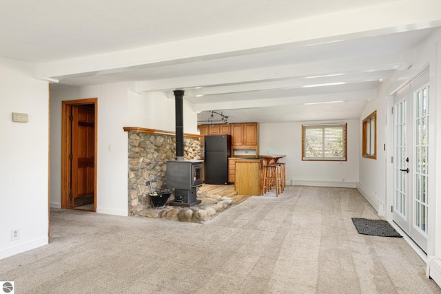 11199 Center Rd, Traverse City, MI 49686 - living room featuring light colored carpet, beamed ceiling, a wood stove, baseboard heating, and baseboards