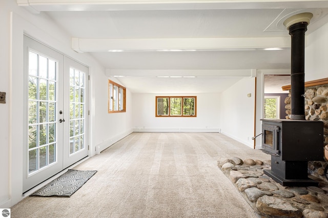 11199 Center Rd, Traverse City, MI 49686 - unfurnished living room featuring beamed ceiling, carpet, a wood stove, french doors, and baseboards