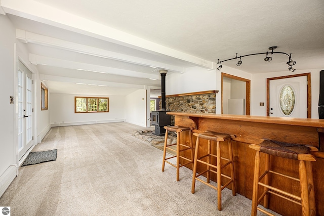 11199 Center Rd, Traverse City, MI 49686 - indoor dry bar with carpet floors, a wood stove, beamed ceiling, and baseboards