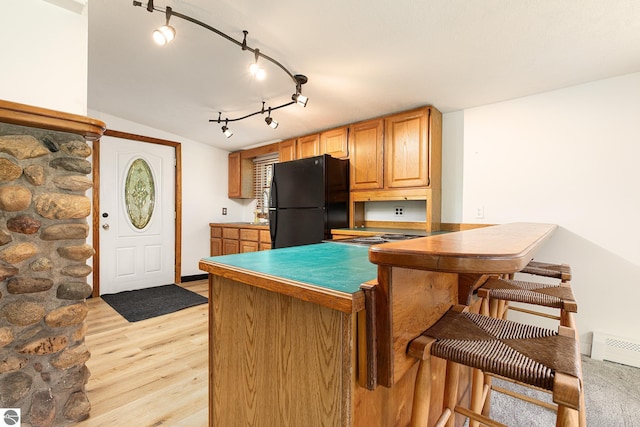 11199 Center Rd, Traverse City, MI 49686 - kitchen with freestanding refrigerator, light wood-style floors, a breakfast bar, a peninsula, and baseboard heating