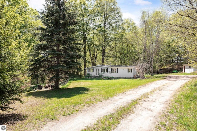 11199 Center Rd, Traverse City, MI 49686 - manufactured / mobile home featuring driveway, a front yard, and a wooded view