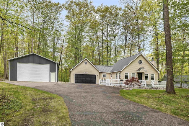 ranch-style home featuring a chimney, a detached garage, covered porch, and metal roof
