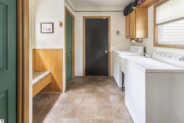 laundry room with wallpapered walls, independent washer and dryer, and cabinet space