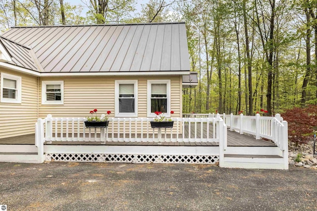 view of front of property featuring a standing seam roof, a wooden deck, and metal roof