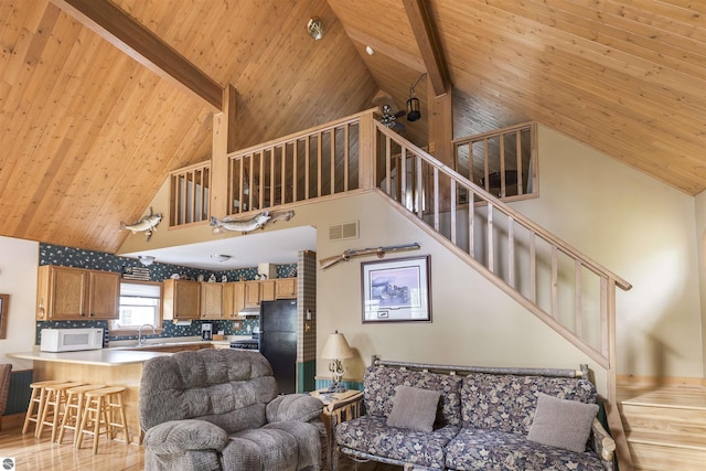 living area featuring wooden ceiling with exposed beams, high vaulted ceiling, light wood finished floors, and stairs