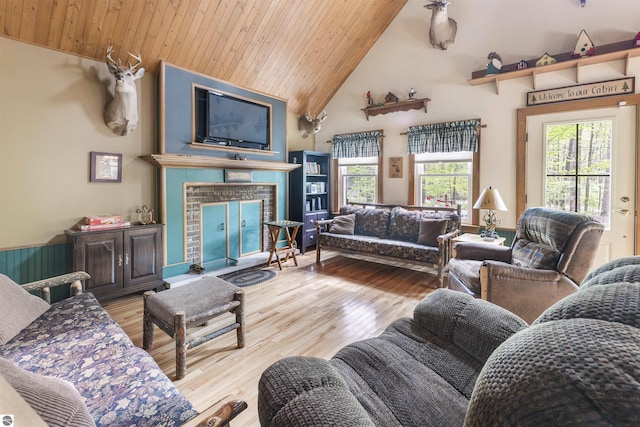 living area featuring wooden ceiling, plenty of natural light, light wood-style flooring, a brick fireplace, and high vaulted ceiling