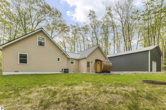 rear view of house with crawl space, a lawn, metal roof, central AC unit, and an outbuilding